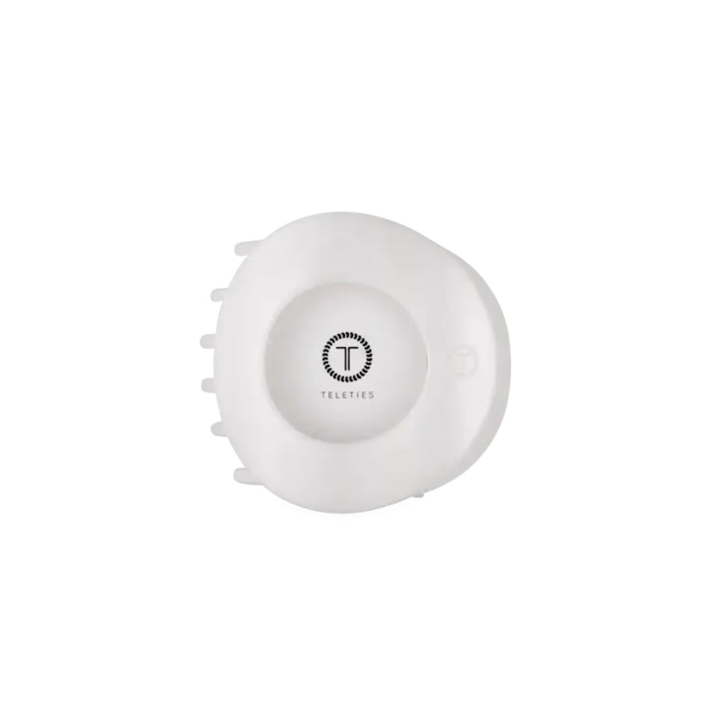 A white circular Teleties hair clip with a central logo and small side tabs, shown on a plain white background.