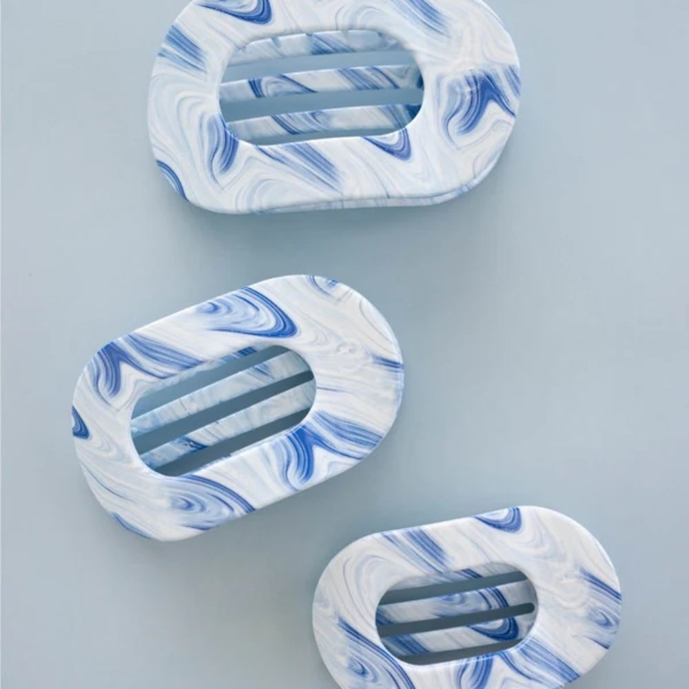 Three marbled blue and white hair clips on a light gray background
