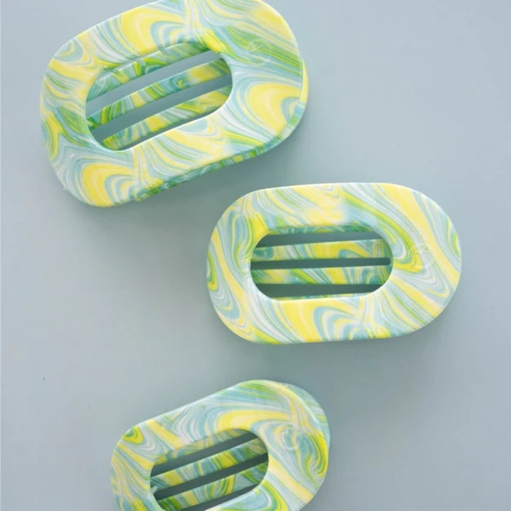 Three marbled hair clips in green and yellow on a light gray background