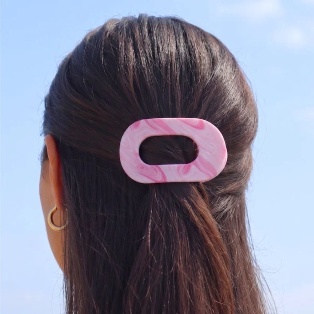 Pink marbled hair clip on a person's hair against a clear blue sky