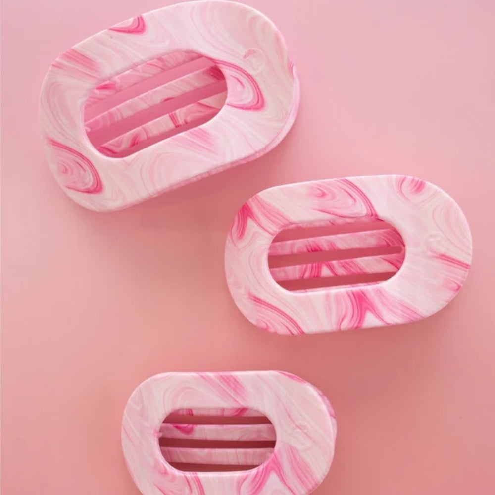 Three pink and white marbled hair clips on a pink background