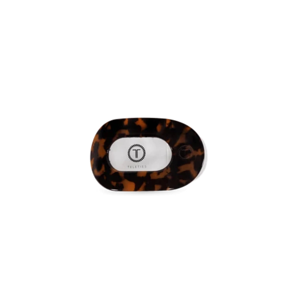 A tortoiseshell baby pacifier with a white center and a circular 'T' logo, photographed on a solid white background.