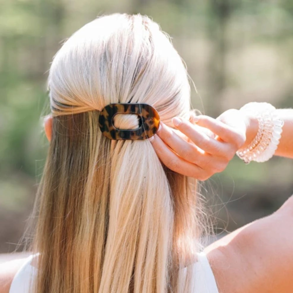 Person with long blonde hair wearing a tortoiseshell hair clip outdoors