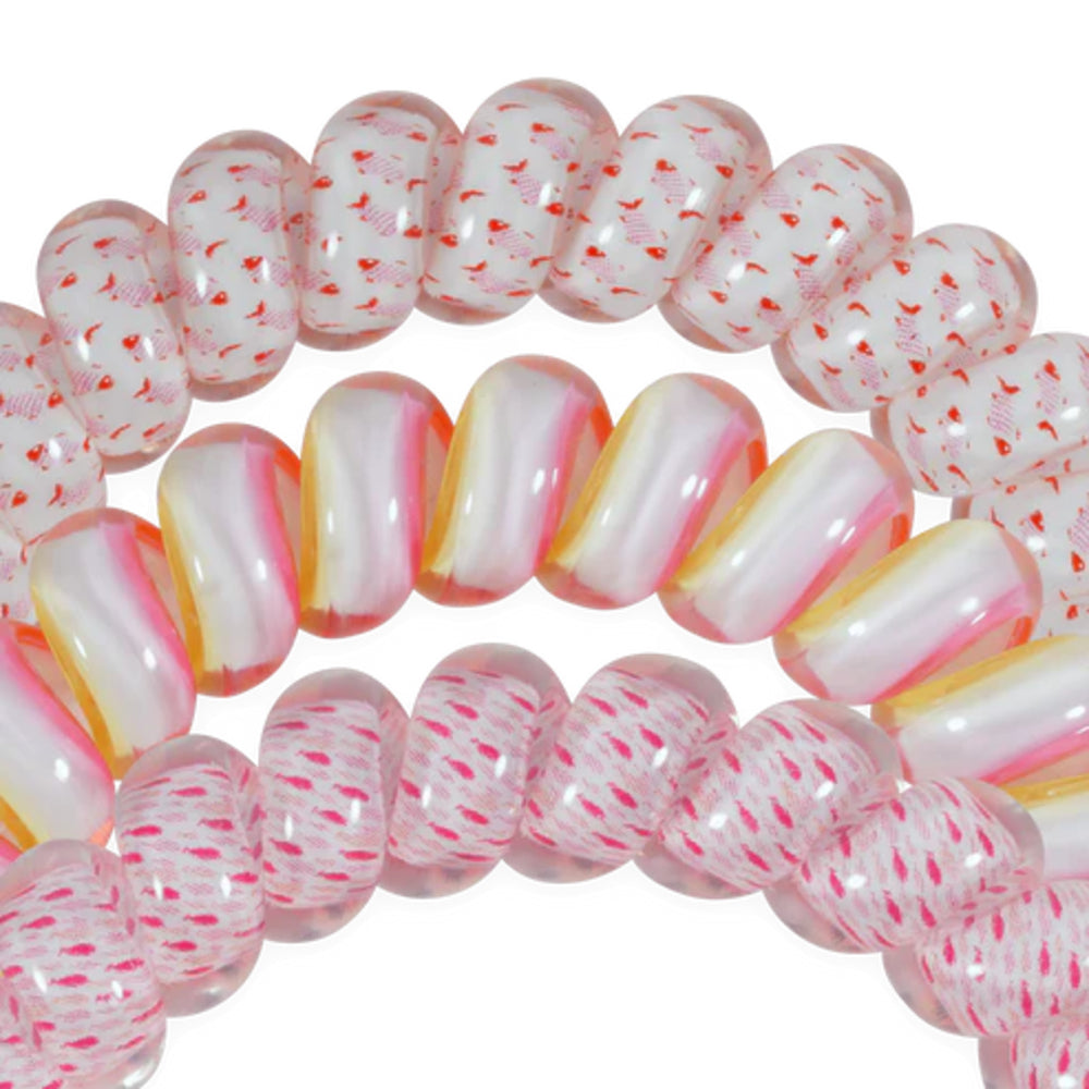 Close-up of pink and white striped hair ties with red specks on a white background