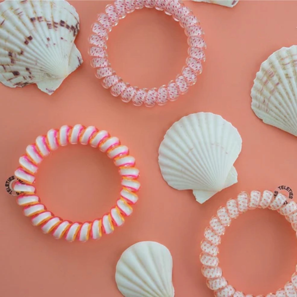 Colorful hair ties with seashells on a peach background