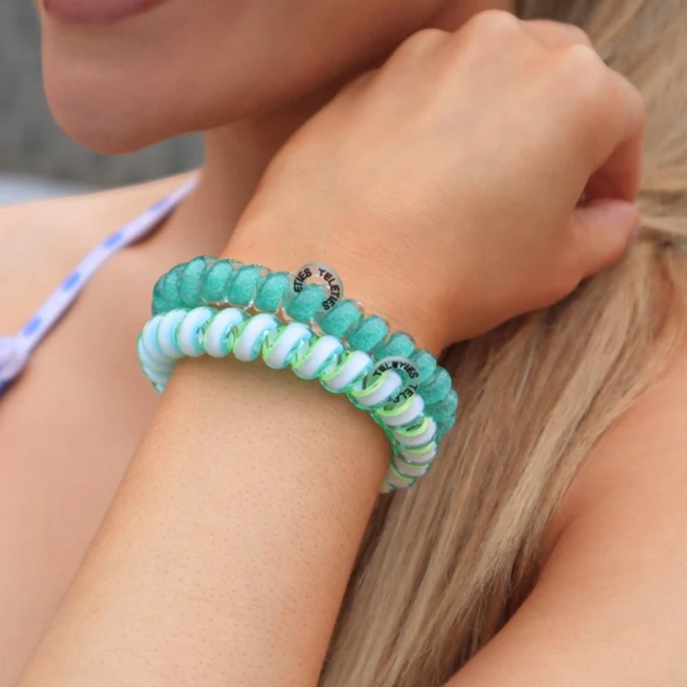 Close-up of a person wearing two turquoise hair ties on a blurred background