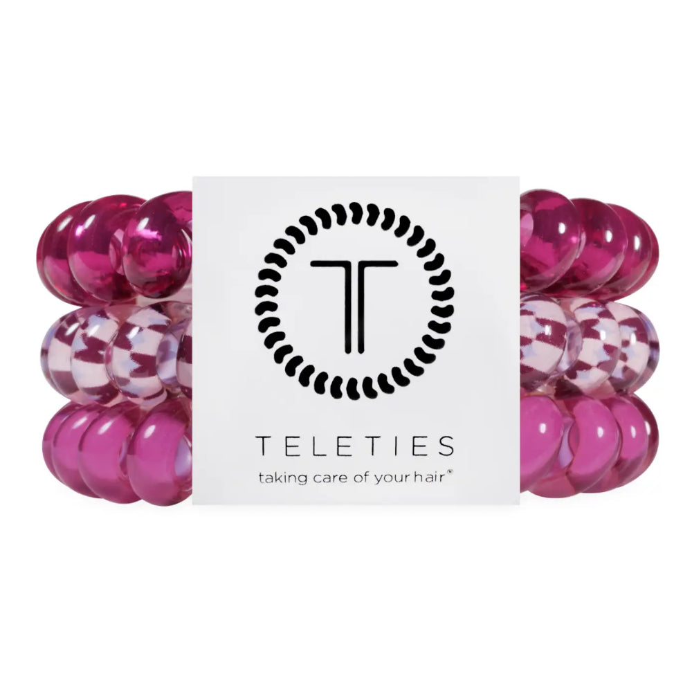 Three metallic magenta hair extension bands flanking a white Teleties brand card, photographed on a clean white background.