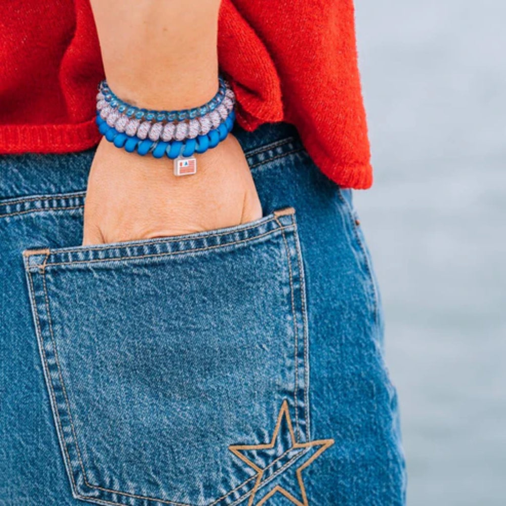 Close-up of blue jeans with a star design and a person wearing a red sweater and blue hair tie.
