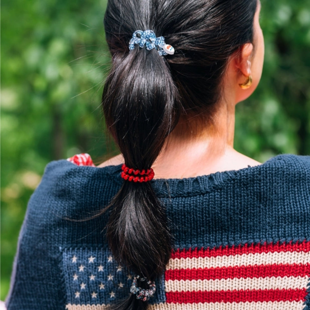 Person wearing a sweater with an American flag design, focusing on the back view with hair ties on hair 