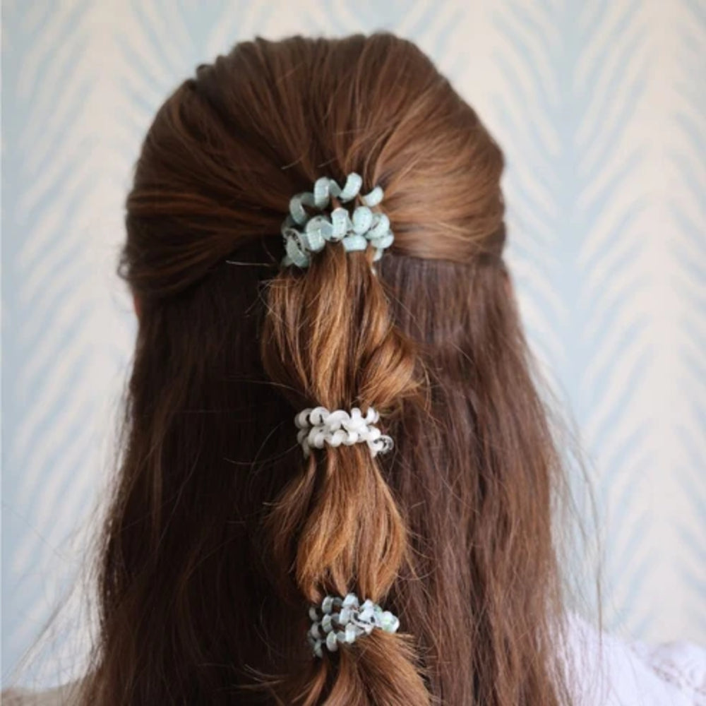 Three fabric hair ties in pale blue and white shown on a model's half-up half-down braid, viewed from behind.