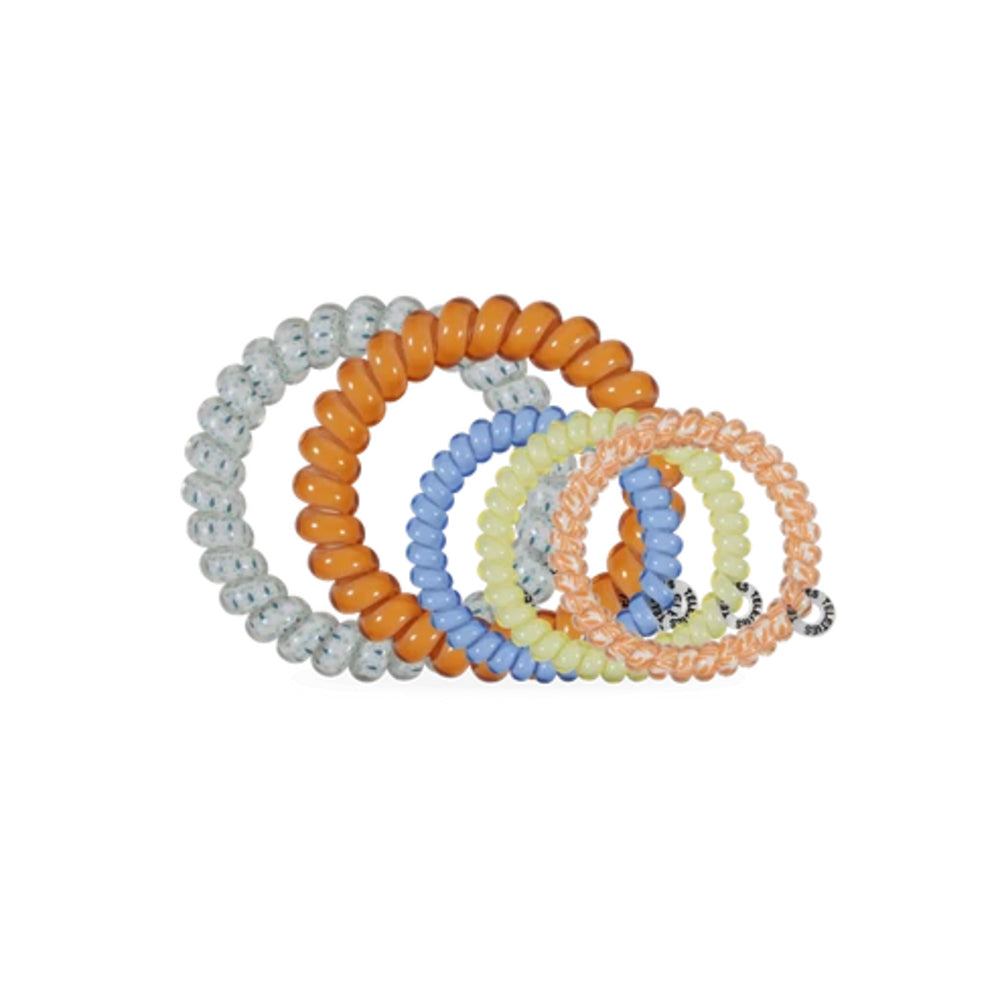 Five coiled beaded hair ties in assorted pastel and bright colors, including orange, light blue, pale yellow, peach, and light gray, arranged on a plain white background.