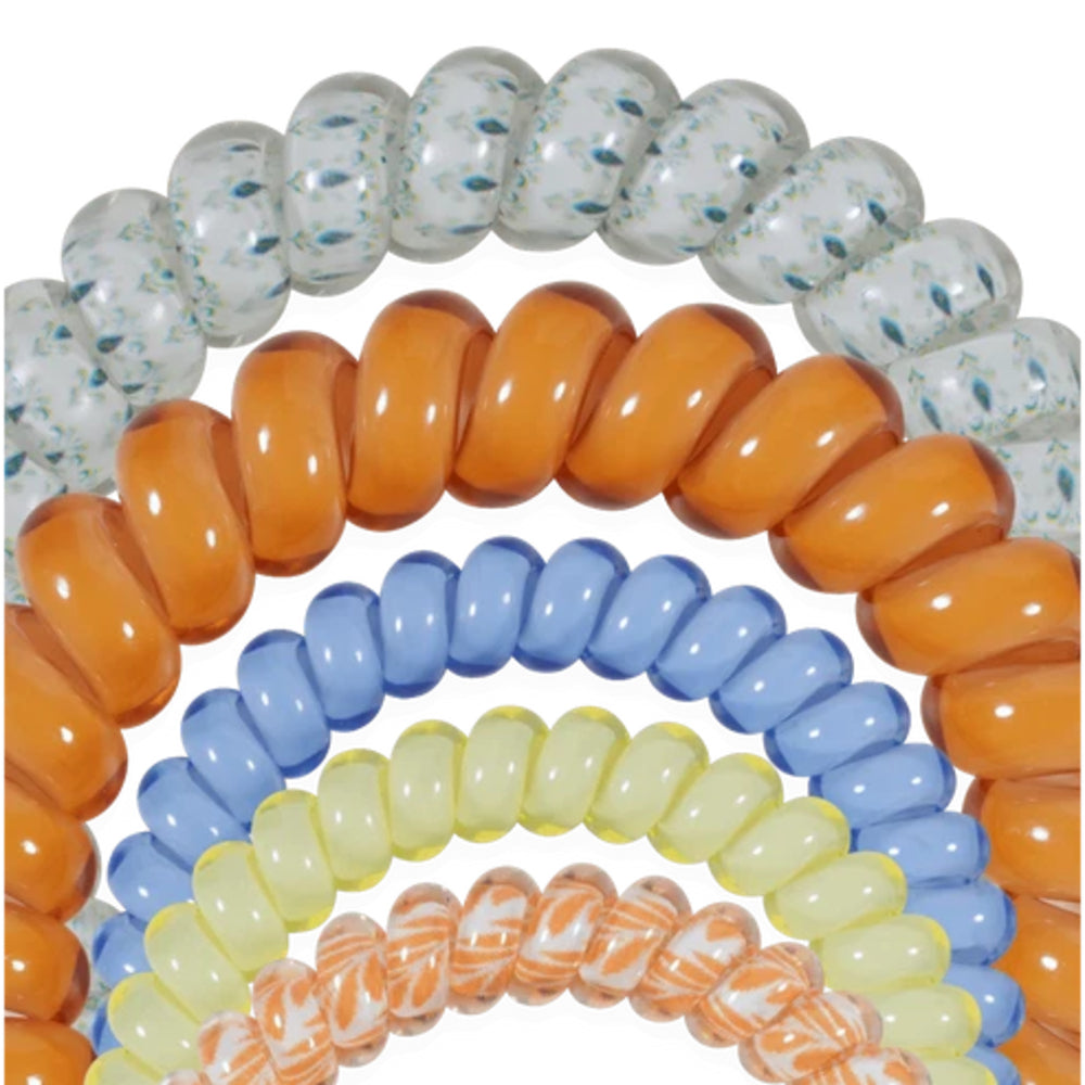 A close-up of multiple coiled glass bead bracelets or elastic bands arranged in overlapping arcs on a white background. The visible colors include white with blue speckling, translucent orange, light blue, pale yellow, and orange-and-white marbled beads.