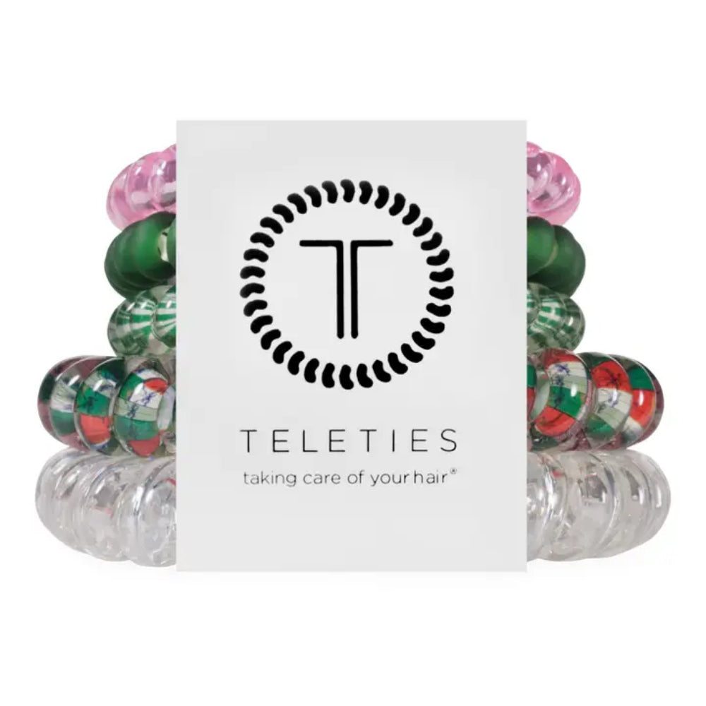 A Teleties hair care product display featuring a central white card with the black Teleties logo and text, surrounded by multiple translucent elastic hair bands in pink, green, and red-and-white striped patterns on a white background.
