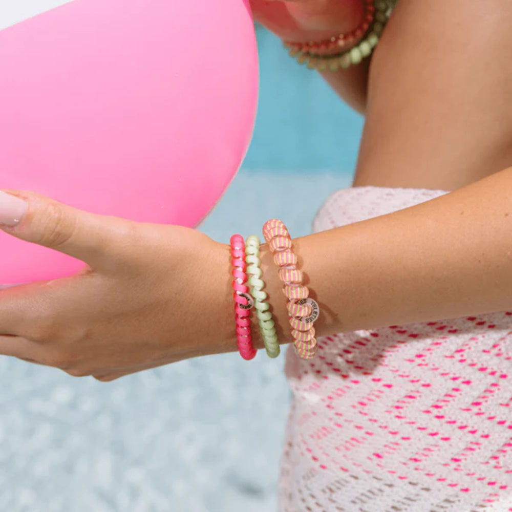 Close-up of a person's wrist wearing colorful beaded bracelets with a blurred background.