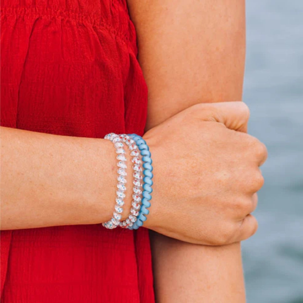 Person wearing two hair ties on a blurred natural background
