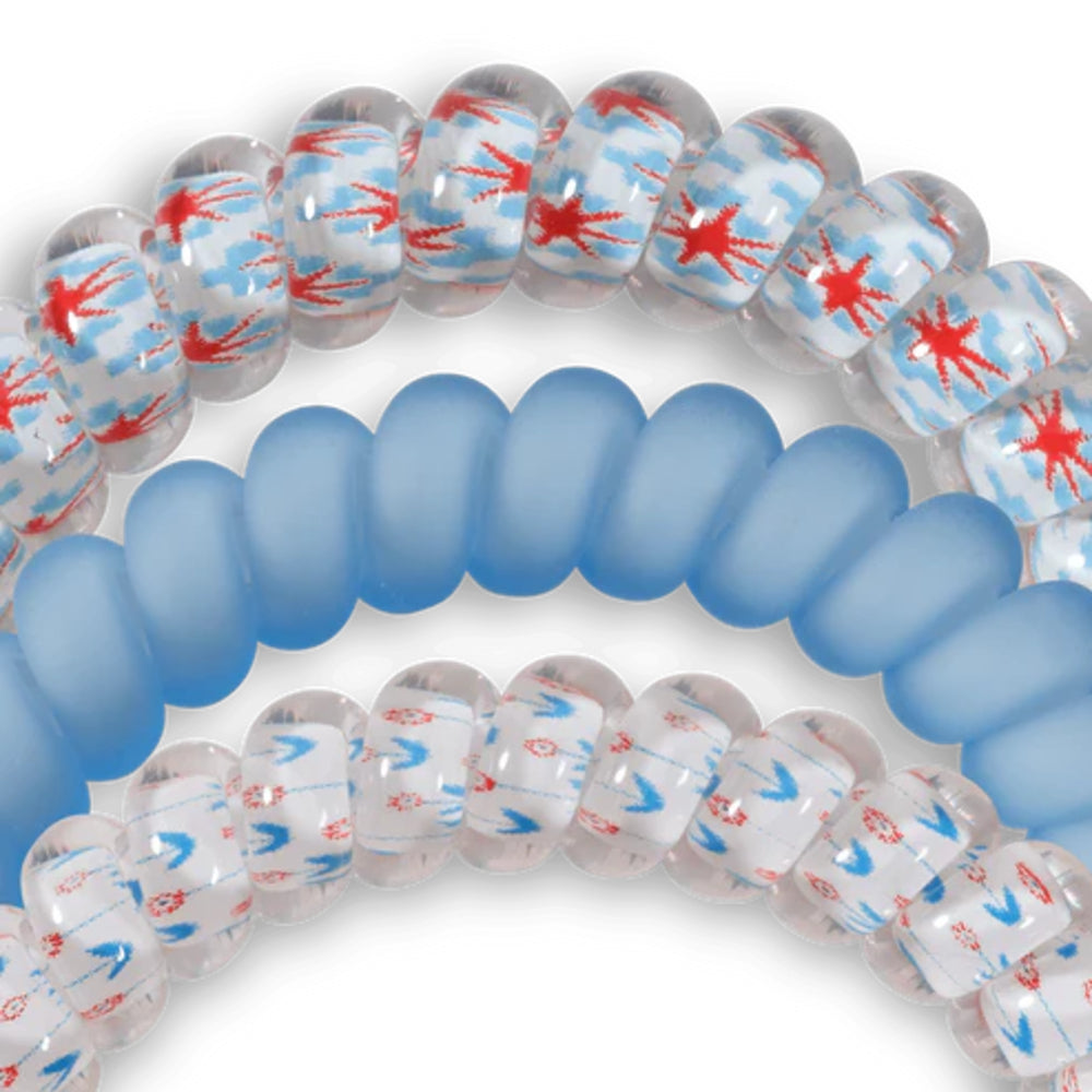 Coiled blue and clear hair ties with red and blue abstract patterns on a white background