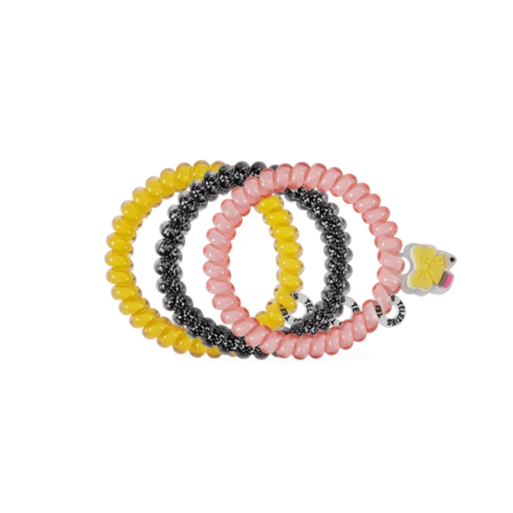 Three beaded spiral hair ties in yellow, black, and pink, arranged in a circle with a small yellow flower charm on the pink one, on a plain white background.