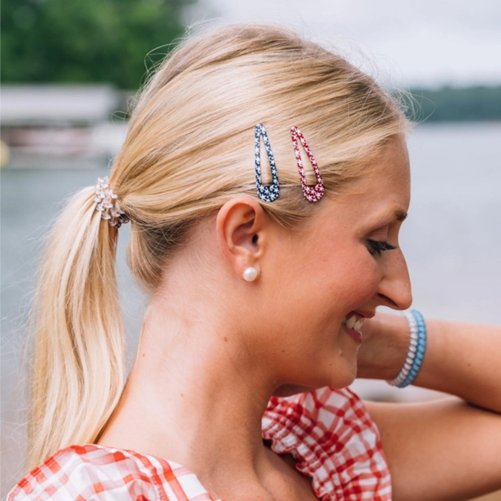 Woman with decorative hair clips and earrings outdoors by a body of water