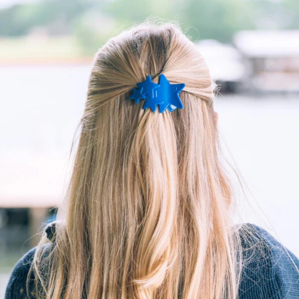 Person with long blonde hair wearing a blue hair clip outdoors