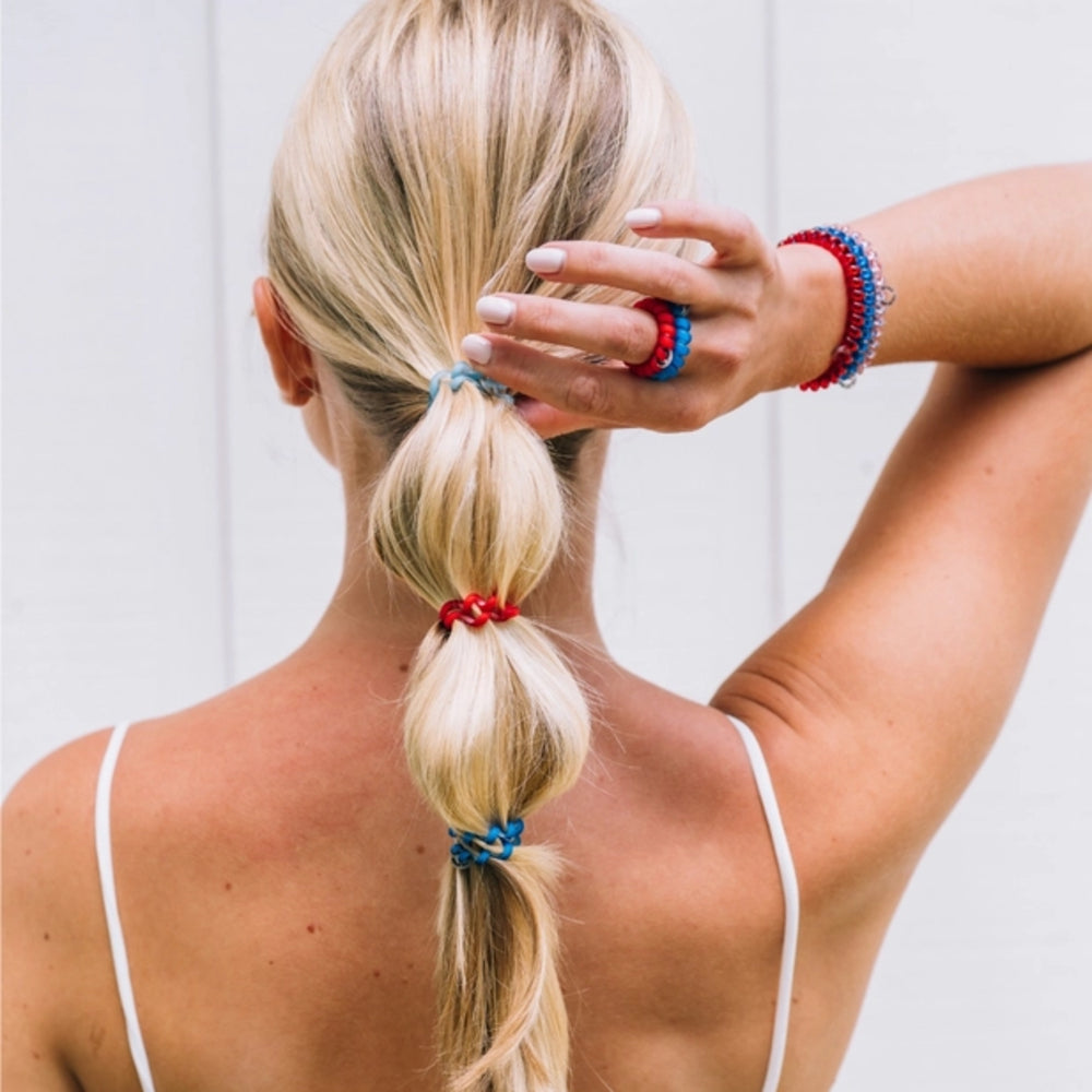 Person with a ponytail using colorful hair ties against a light background
