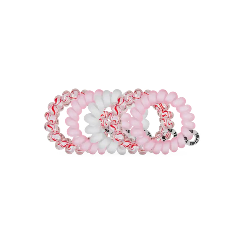 Five hair stretch bands arranged in a circle on a plain white background. Two bands are light pink with red swirls, one band is solid white, and one band is light pink with clear beads.