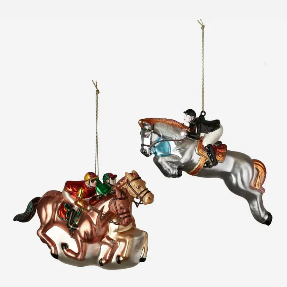 Two hanging horse-and-rider ornaments on a plain light gray background. One ornament shows a brown horse with a rider in red and green clothing.