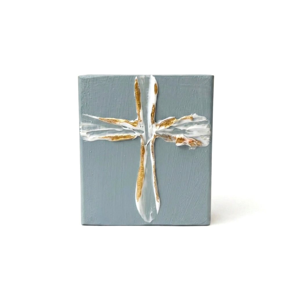 Decorative blue wood block with a gold and white cross on a white background