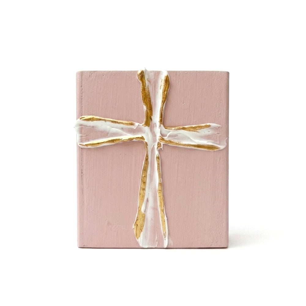 Decorative pink wood block with a gold and white cross on a white background