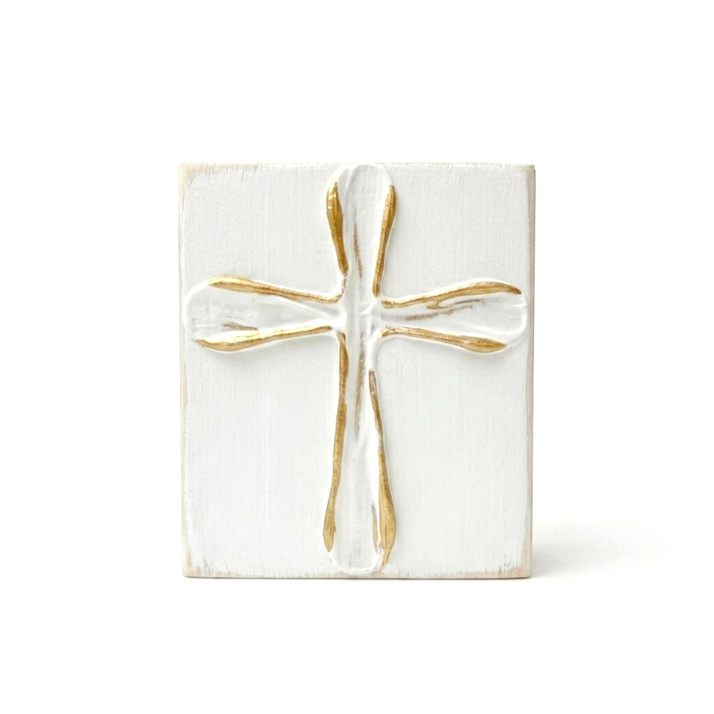 Decorative white wood block with a gold and white cross on a white background