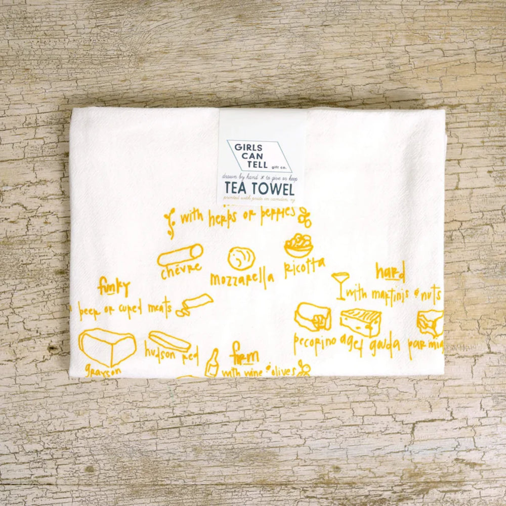 White tea towel with yellow text and illustrations on a wooden surface