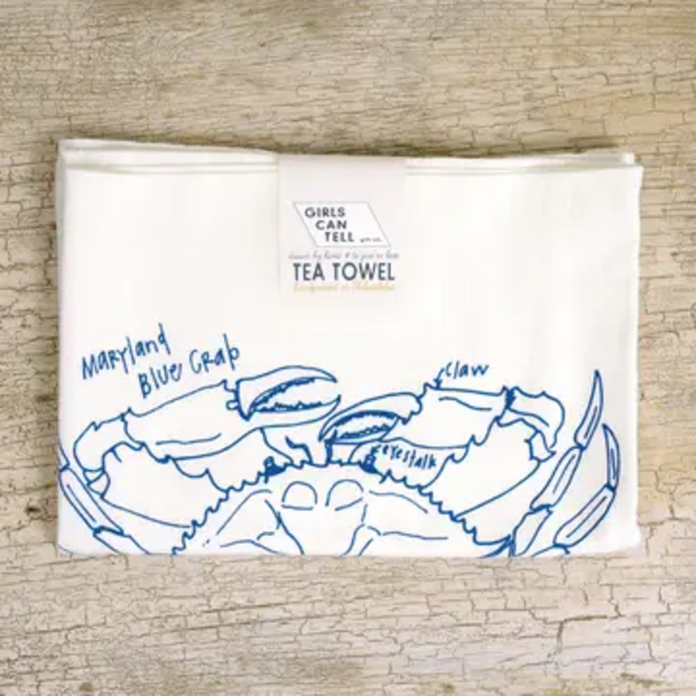 Tea towel with blue crab design and text on a wooden surface