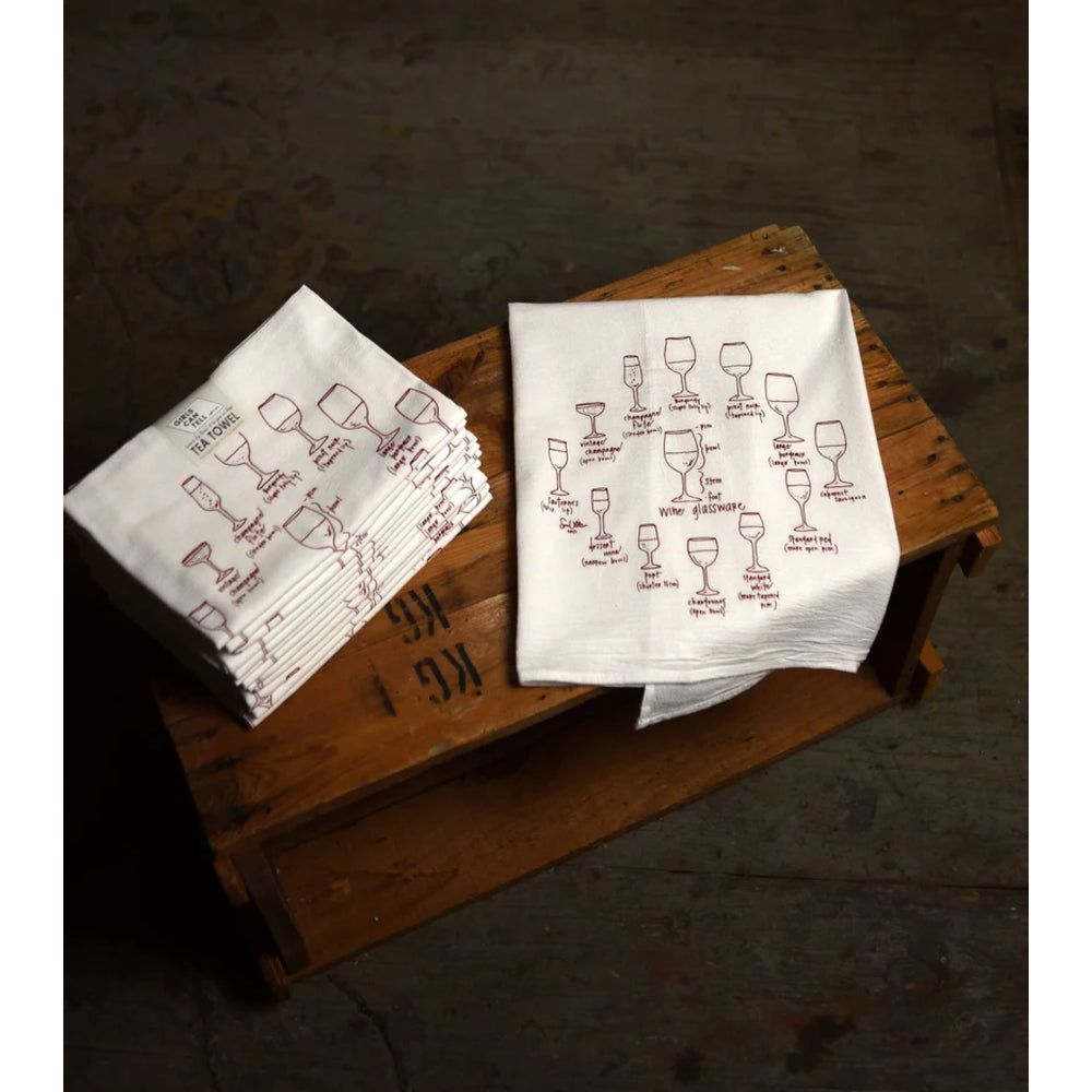 Two white napkins with red wine glass illustrations on a wooden surface.