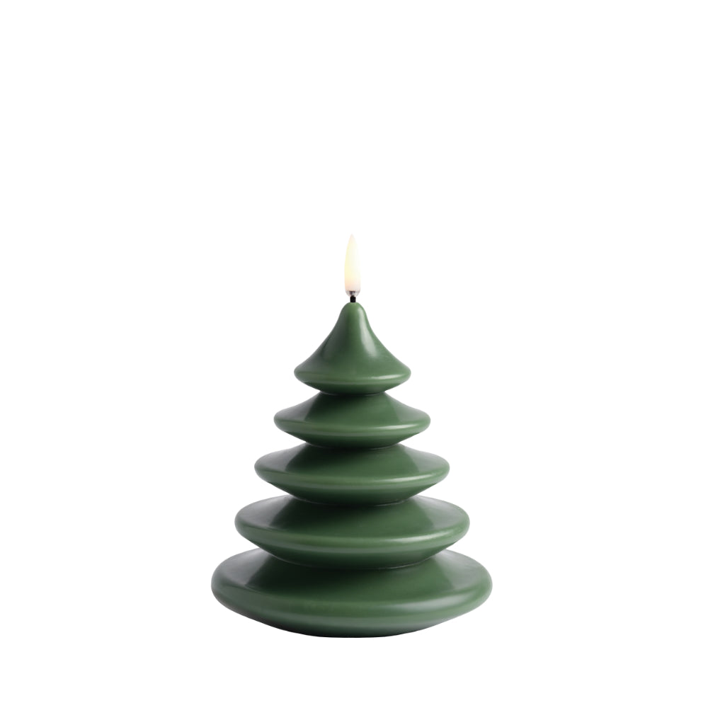 A tree-shaped candle made of stacked, tiered discs in a matte dark green color, with a small white flame at the top, isolated on a white background.