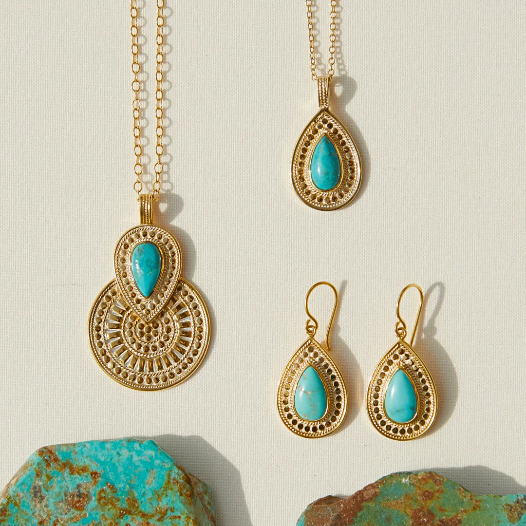 Gold necklace and earrings with turquoise stones on a beige background