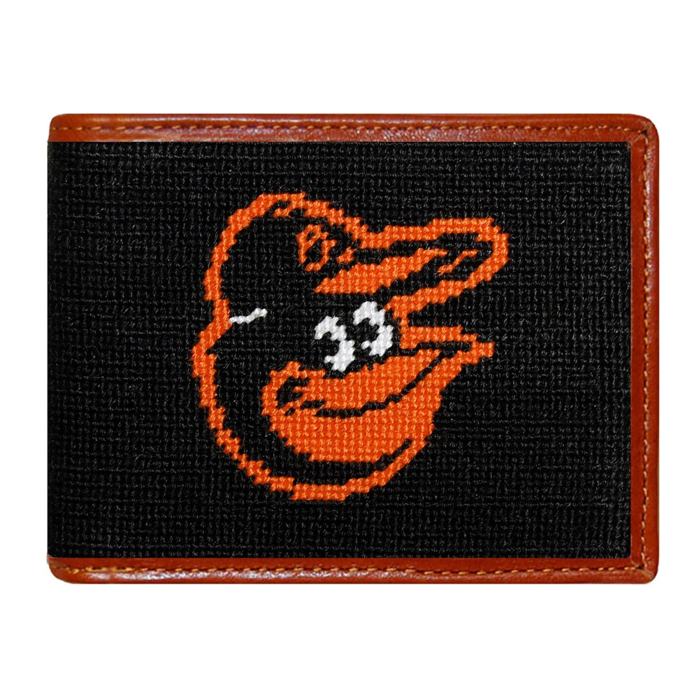 A black canvas bi-fold wallet with a brown leather border and a stitched Baltimore Orioles bird logo on the front.