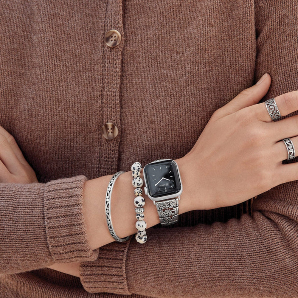 Person wearing a smartwatch and bracelets on a brown background