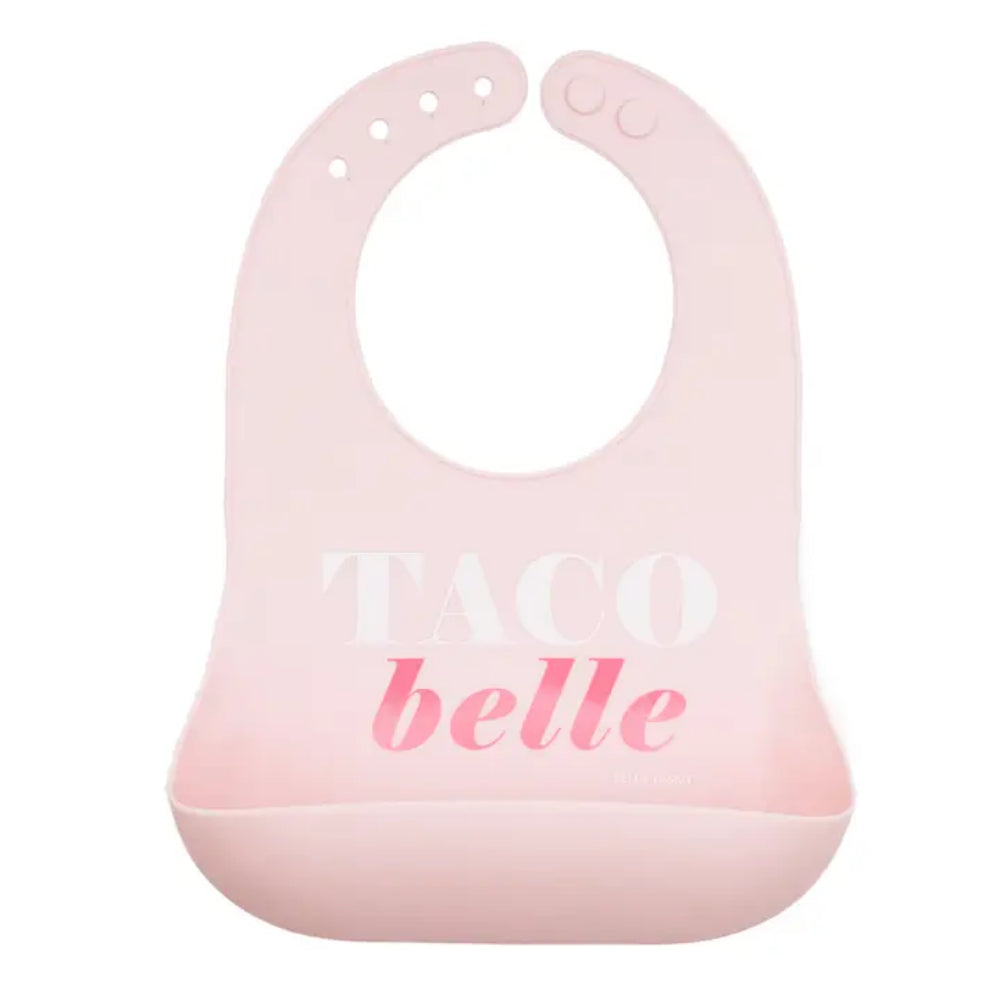 A light pink silicone baby bib with a suction cup base and the words 'TACO belle' printed on the front, shown against a plain white background.