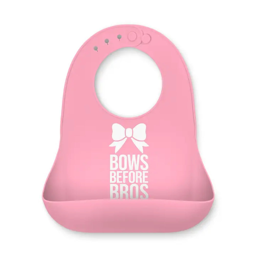 A pink silicone baby bib with a white bow graphic and the text 'BOWS BEFORE BROS' printed on the front, set against a plain white background.