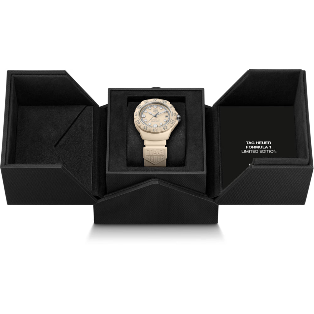 Gold watch in a black box with 'TAG Heuer' branding on a white background