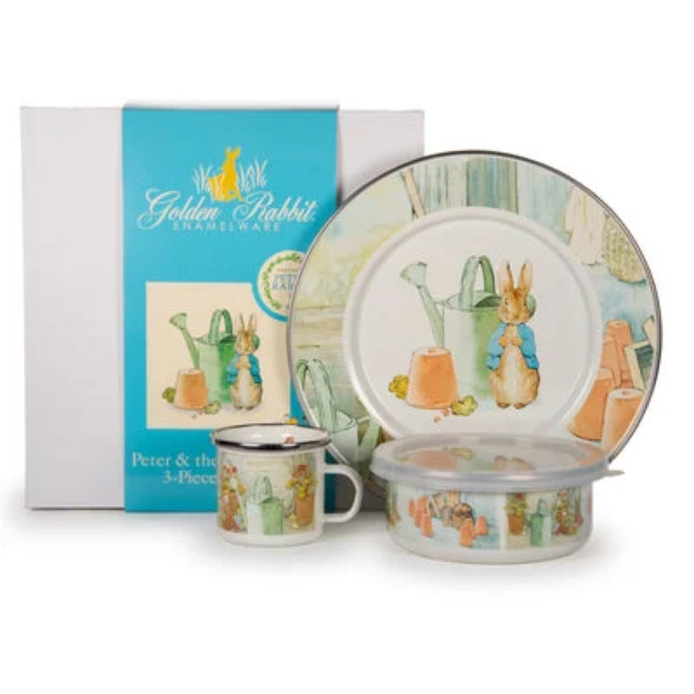 Children's enamelware set with 'Peter Rabbit' design, including a mug, plate, and bowl, in front of its packaging.