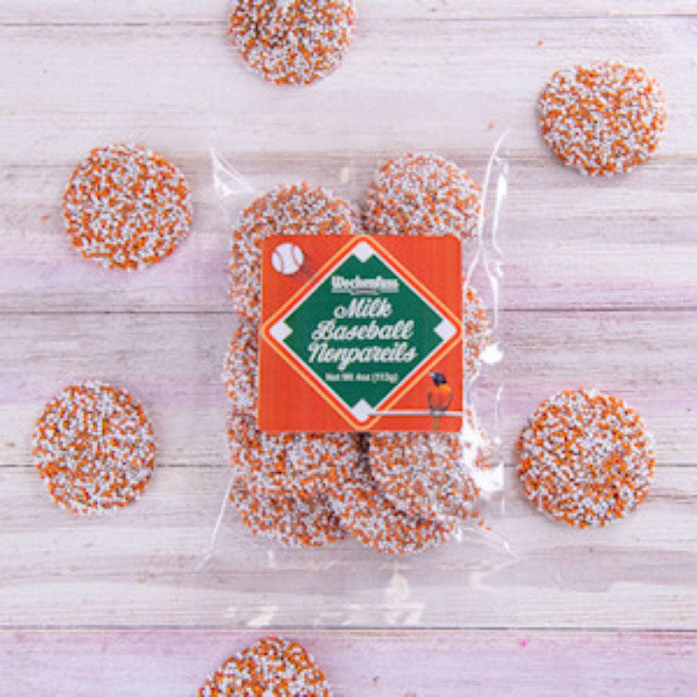 Packaged milk baseball nonpareils with decorative sprinkles on a wooden surface.