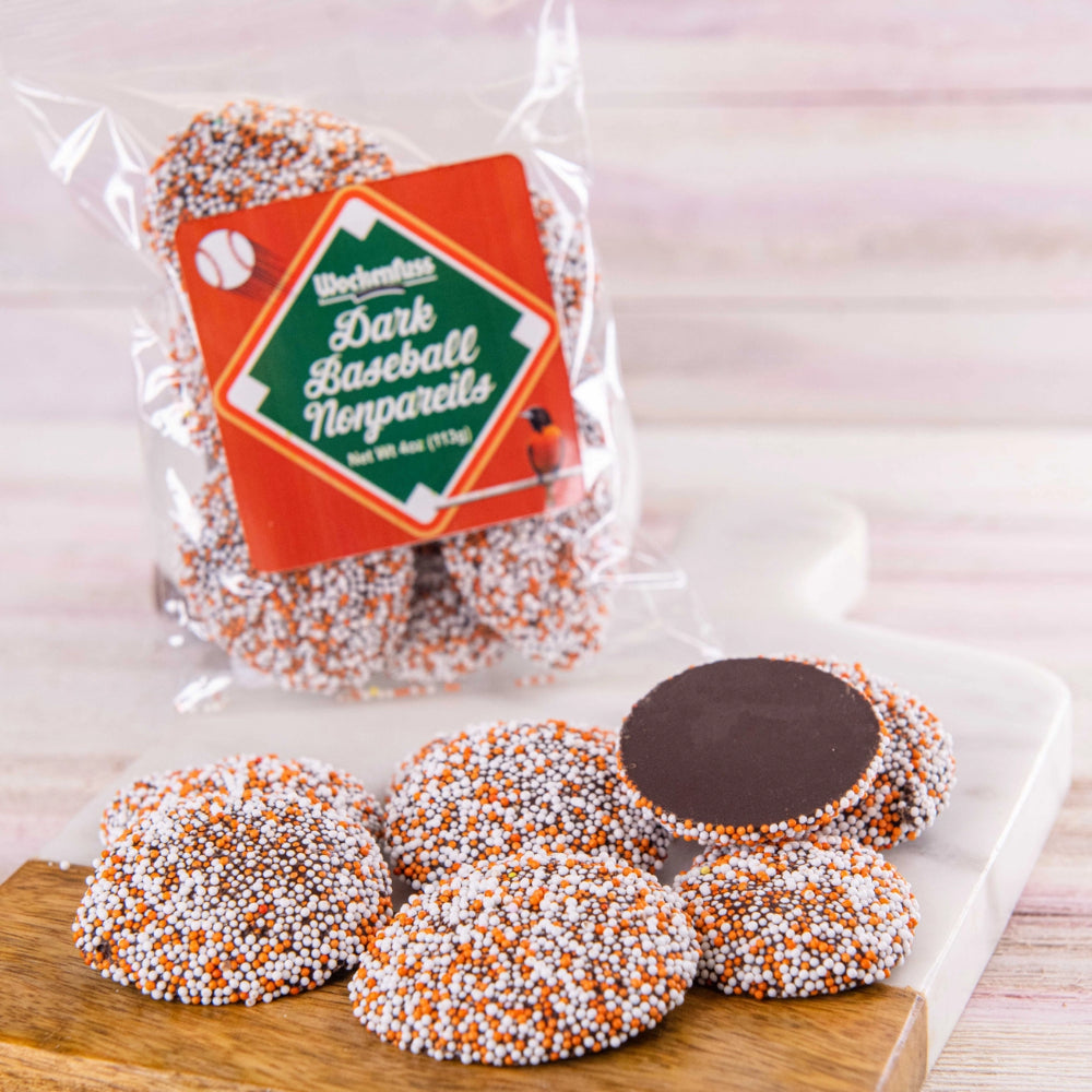 Packaged dark baseball nonpareils with a clear wrapper on a wooden surface.