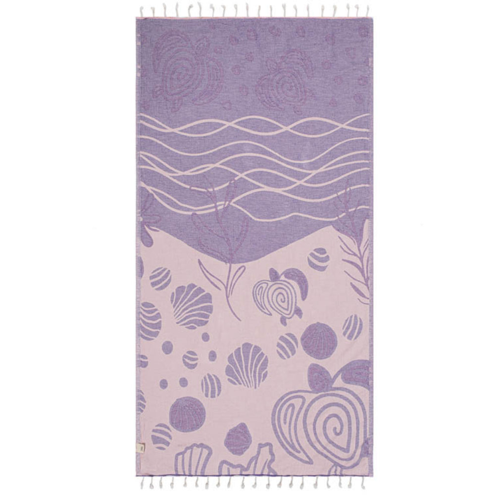 Side two of a purple and pink beach towel with a wave, shell,  and sea turtle pattern with a white tassel edge on a white background.