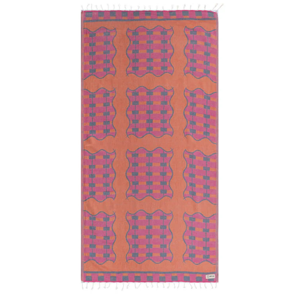 A photo of side one of a reversible patterned towel with a colorful  pink and blue geometric design on  a orange base  on a white background.