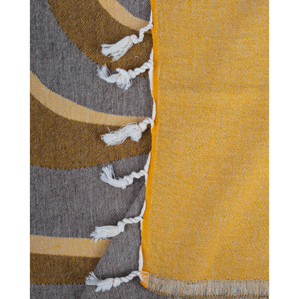 A close up photo of a multicolored yellow and grey beach towel with white tassels on a white background.