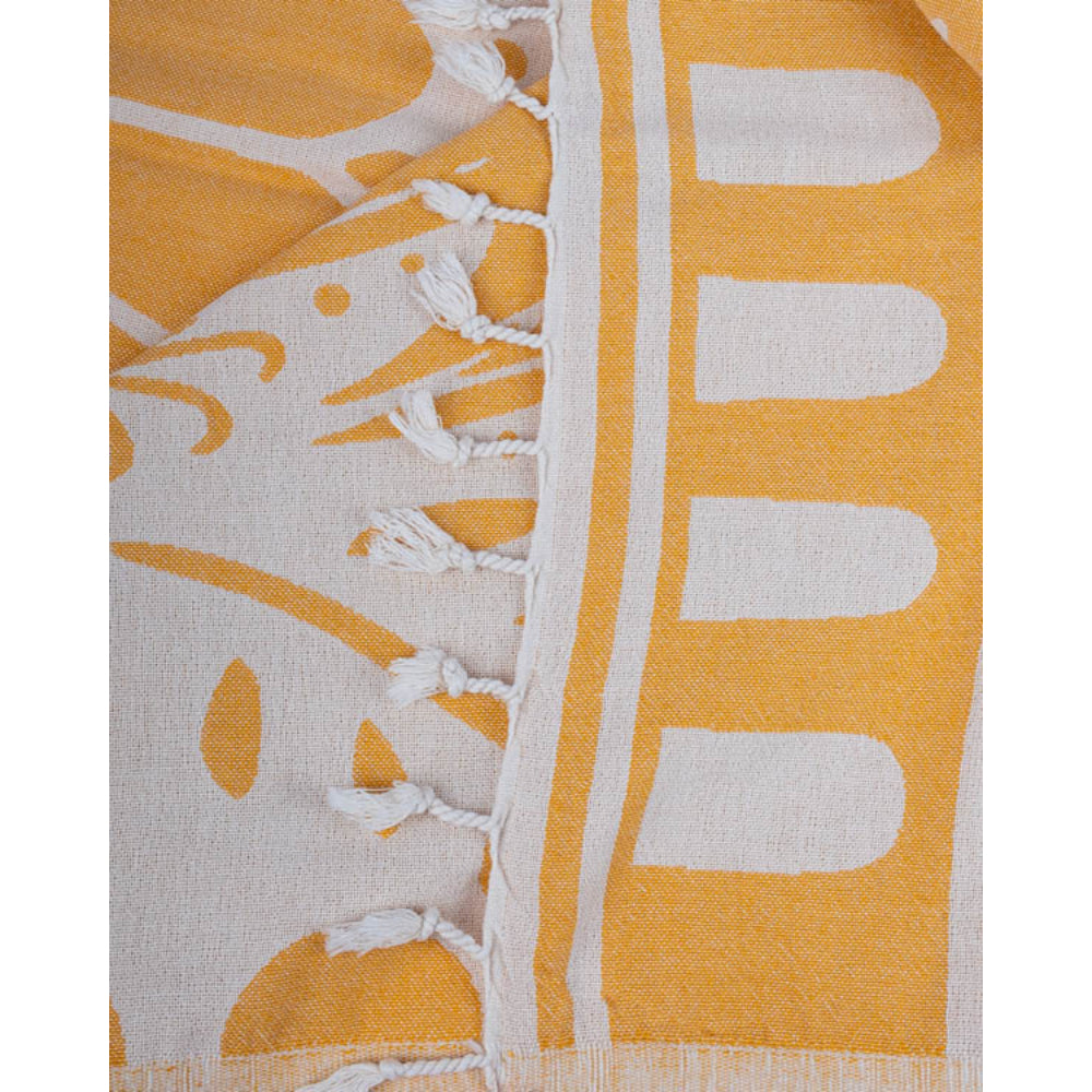 A close-up of a yellow and white reversible patterned beach towel with white tassel edge on a white background.