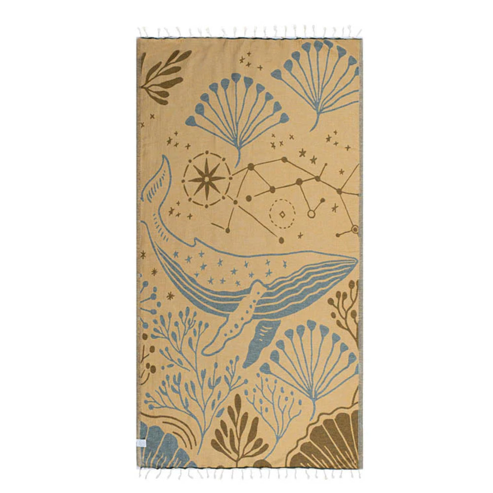 Side two of a beige beach towel with blue whale and star constellation design on a white background.