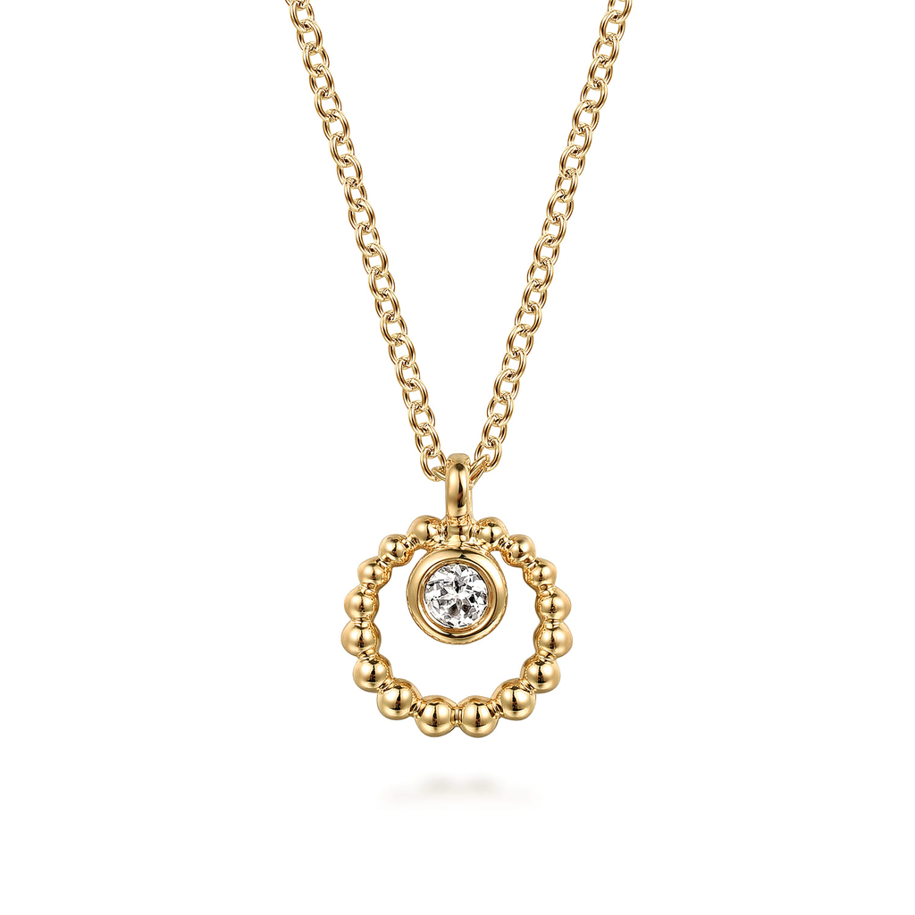 gold pendant necklace with center gemstone on white background