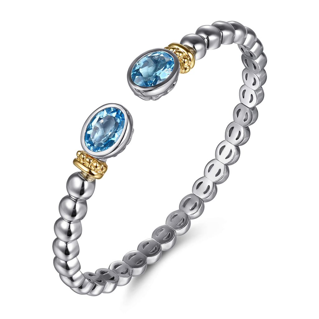 Silver ring with blue gemstones and gold accents on a white background