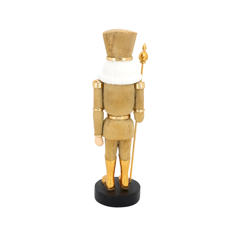 A gold metallic nutcracker figurine shown from the back, wearing a gold uniform with a white collar and holding a gold spear, standing on a black base against a white background.